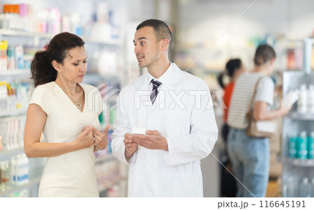 Male pharmacist advises medicine for heart pain to woman Male pharmacist advises medicine for heart pain to woman 116645191