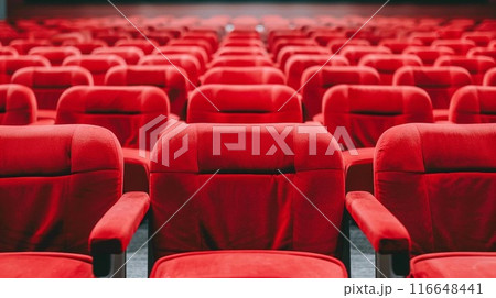 Rows of empty red theater seats in a darkened movie theater. 116648441
