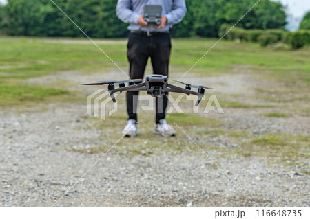 ホバリングするドローンと操縦する男性 116648735