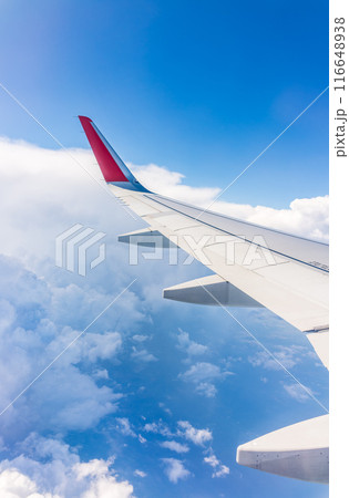 View from the airplane window at a beautiful cloudy sky and the airplane wing 116648938