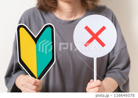 初心者マークと×のプレートを持つ女性 116649378