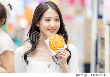 観光をしながら食べ歩きをする若い女性 116649617