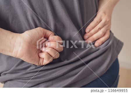 痛そうに腰に手を当てる女性 116649955