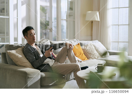 young asian man using mobile phone at home young asian man using mobile phone at home 116650094