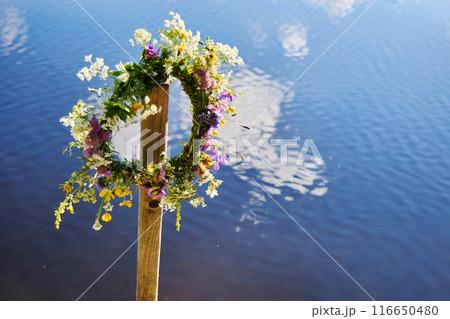 Midsummer background. Floral Wreath by the Water 116650480
