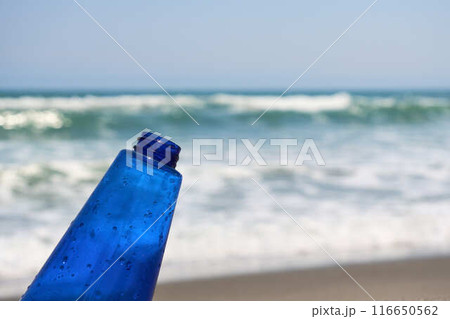 波が打ち寄せる砂浜と青いボトル 116650562