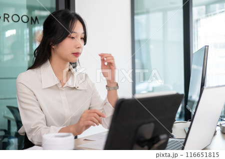 Young woman examines stock graphs at office desk Young woman examines stock graphs at office desk 116651815