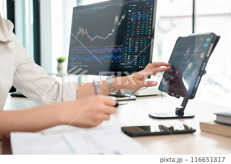Young woman examines stock graphs at tablet 116651817