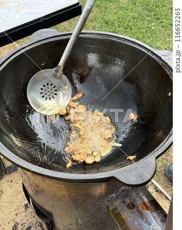 A man fries onions in oil on a hot grill. Brazier on an open fire. Close-up. 116652265