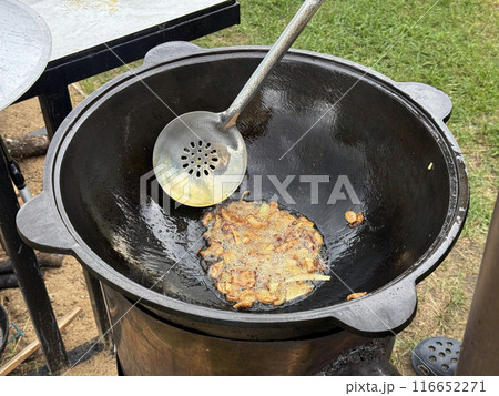 A man fries onions in oil on a hot grill. Brazier on an open fire. Close-up. 116652271