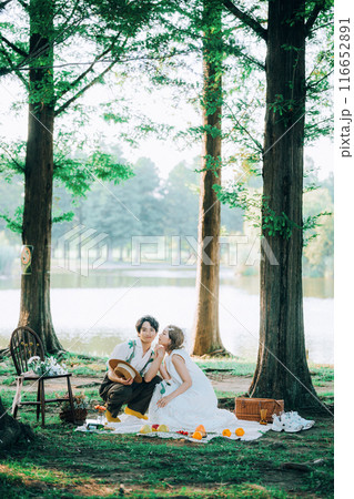ピクニックをしながら前撮り撮影をする新郎新婦 116652891