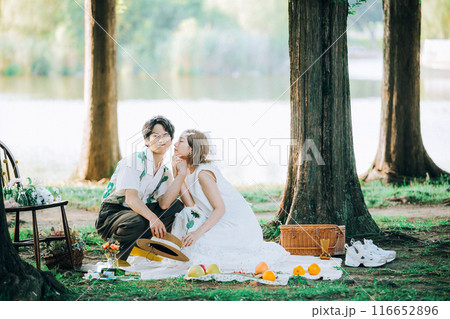 ピクニックをしながら前撮り撮影をする新郎新婦 116652896