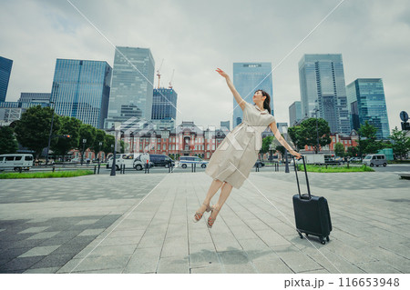 キャリーバッグをひいて旅にでた、若い女性の心弾む様子 116653948