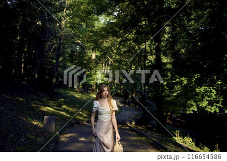 beautiful teenage girl in a silk skirt and a corset in the old money style walks in the park and along the river bank beautiful teenage girl in a silk skirt and a corset in the old money style walks in the park and along the river bank 116654586