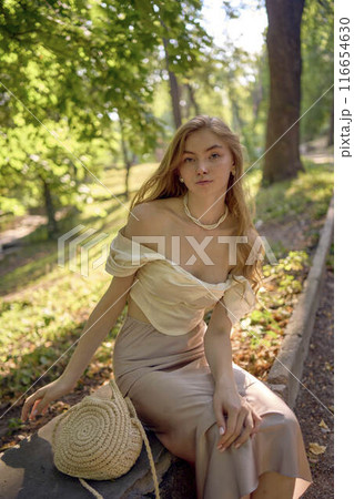 beautiful teenage girl in a silk skirt and a corset in the old money style walks in the park and along the river bank beautiful teenage girl in a silk skirt and a corset in the old money style walks in the park and along the river bank 116654630