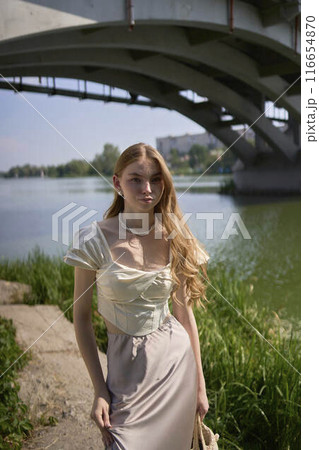 beautiful teenage girl in a silk skirt and corset in the old money style.  Fashion photoshoot under the bridge. 116654870
