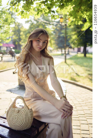 a beautiful teenage girl in a peach fuzz suit with a waistcoat, in the old money style  walks through the morning city 116654939