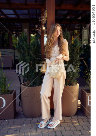 a  beautiful teenage girl in a peach fuzz suit with a vest, in the old money style in a fancy restaurant 116654951
