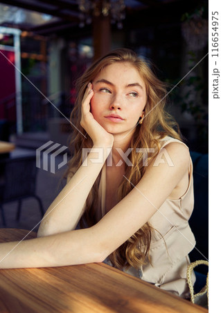 a  beautiful teenage girl in a peach fuzz suit with a vest, in the old money style in a fancy restaurant 116654975