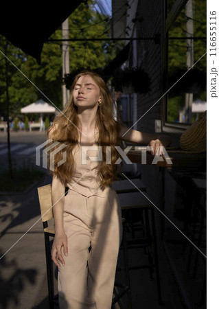 a beautiful teenage girl in a peach fuzz suit with a waistcoat in the old money style sits at the bar outside a beautiful teenage girl in a peach fuzz suit with a waistcoat in the old money style sits at the bar outside 116655116