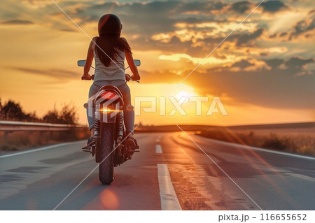 Rear view of a young woman riding a motorcycle on the road at sunset Rear view of a young woman riding a motorcycle on the road at sunset 116655652