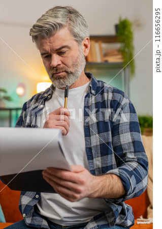 Mature man with documents analyzing information reading business papers prepare financial report Mature man with documents analyzing information reading business papers prepare financial report 116656295