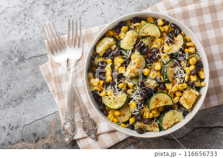 Roasted Zucchini salad with black beans, corn, garlic and cheese close-up in a bowl. Horizontal top view 116656733