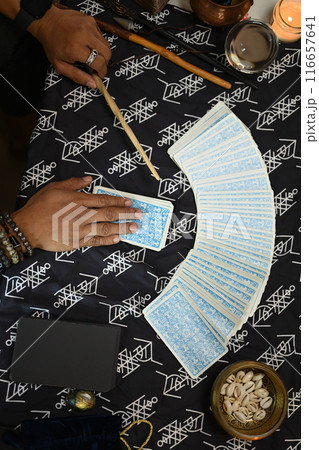 Overhead shot of fortune teller spreading Tarot cards laid out on a table covered with mystical cloth 116657641