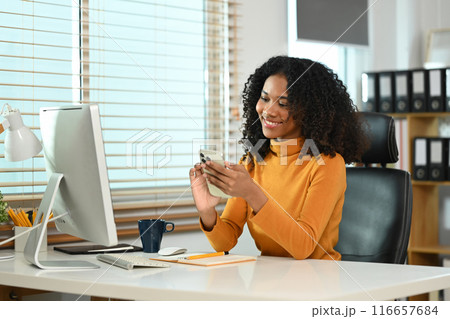 Satisfied female entrepreneur taking a break from her work and using mobile phone 116657684