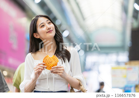 観光をしながら食べ歩きをする若い女性 116657876