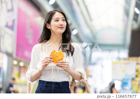 観光をしながら食べ歩きをする若い女性 観光をしながら食べ歩きをする若い女性 116657877