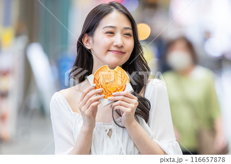 観光をしながら食べ歩きをする若い女性 116657878