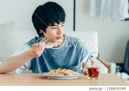 チャーハンを食べながらスマホを見る若い男性 チャーハンを食べながらスマホを見る若い男性 116659249