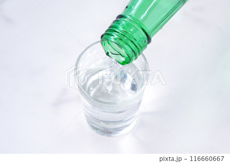 韓国の伝統的な蒸留酒、よく冷えた韓国焼酎（ソジュ）をグラスに注ぐ 116660667