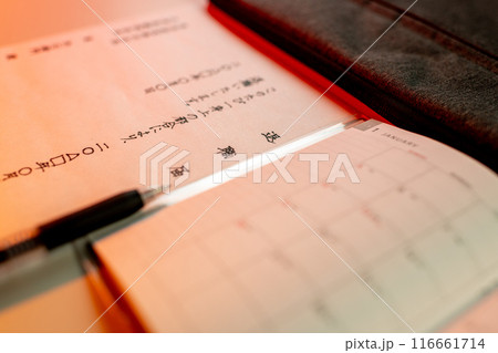 赤い光に照らされた手書きの退職届とゲルインクの黒ペンと新しいスケジュール帳 116661714