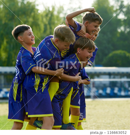 Smiling friends, boys jumping and hugging, expressing happiness and excitement after winning soccer game on outdoor stadium Smiling friends, boys jumping and hugging, expressing happiness and excitement after winning soccer game on outdoor stadium 116663052