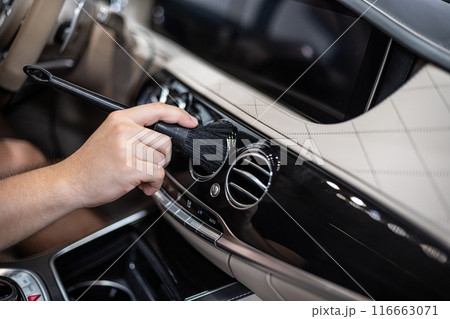 Detailing interior car dashboard using brush, ensuring thorough cleaning and high-quality finish Detailing interior car dashboard using brush, ensuring thorough cleaning and high-quality finish 116663071