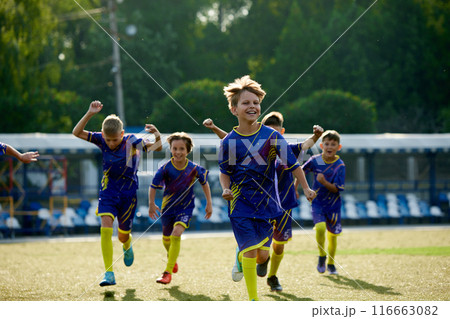 Happy and excited boys, children in sportswear running on field, expressing happiness and success after winning match. Team spirit. Happy and excited boys, children in sportswear running on field, expressing happiness and success after winning match. Team spirit. 116663082