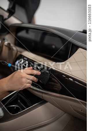 Detailing interior car dashboard using brush, ensuring thorough cleaning and high-quality finish 116663083