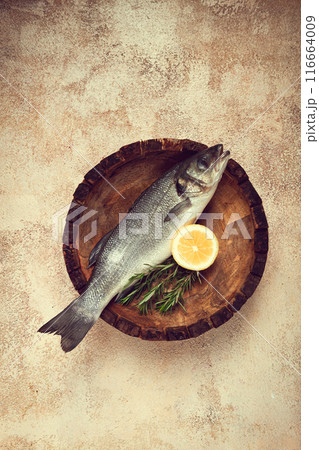 fresh, raw sea bass fish, in a wooden plate, top view, no people. 116664009