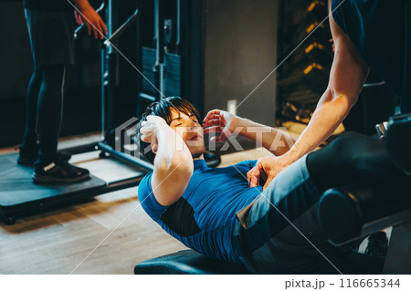 フィットネスジムでトレーナーの指導を受ける男性 116665344