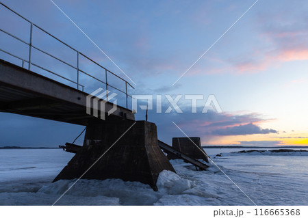 Broken pier is under sunset sky, coastal winter landscape Broken pier is under sunset sky, coastal winter landscape 116665368