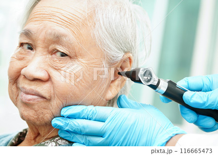Otolaryngologist or ENT physician doctor examining senior patient ear with otoscope, hearing loss problem. Otolaryngologist or ENT physician doctor examining senior patient ear with otoscope, hearing loss problem. 116665473