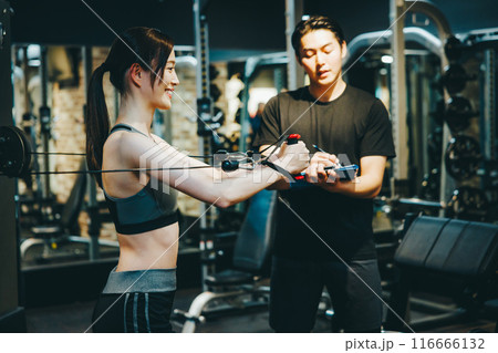 フィットネスジムでトレーナーの指導を受ける女性 116666132