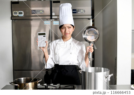鍋と電卓を持ち悩むアジア人の女性調理師 116666453