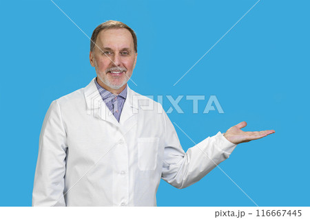 Happy smiling male senior male doctor showing a copy space. Isolated on blue. 116667445