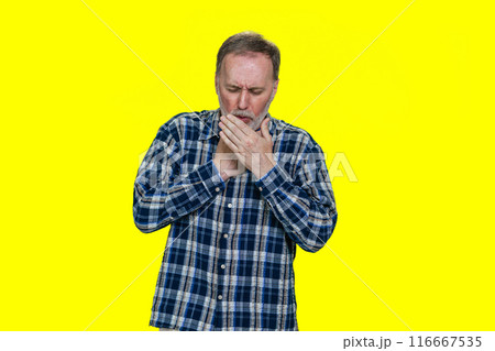 Portrait of a sick coughing mature senior man. Isolated on yellow. 116667535