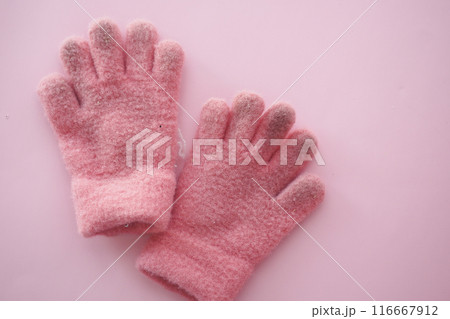 Cozy pink fluffy gloves on pink background, ideal for winter, keeping hands warm and stylish 116667912