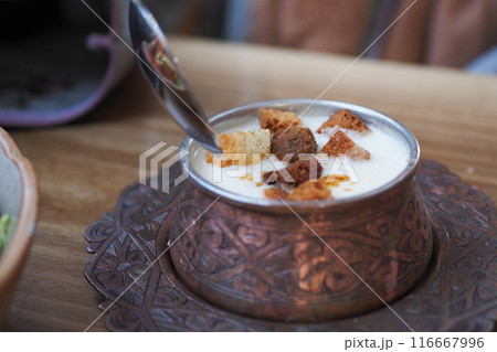 woman eating yogurt soup, traditional soup with chickpeas and mint. 116667996