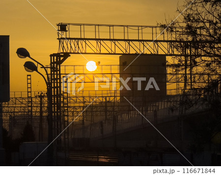 Urban railway infrastructure at sunset with industrial structures Urban railway infrastructure at sunset with industrial structures 116671844